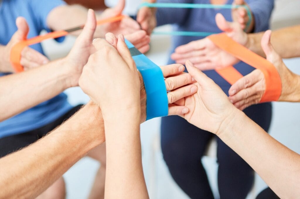 Trainer hilft bei Übung mit dem Elastikband