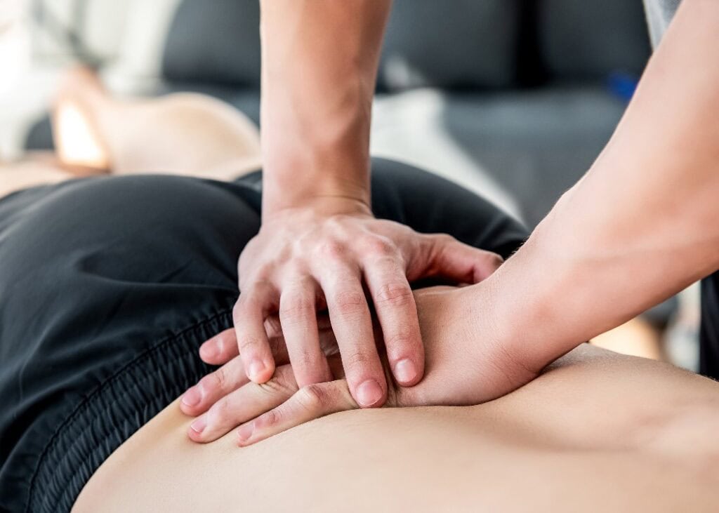 Therapeut bei der Sportmassage des unteren Rückens.